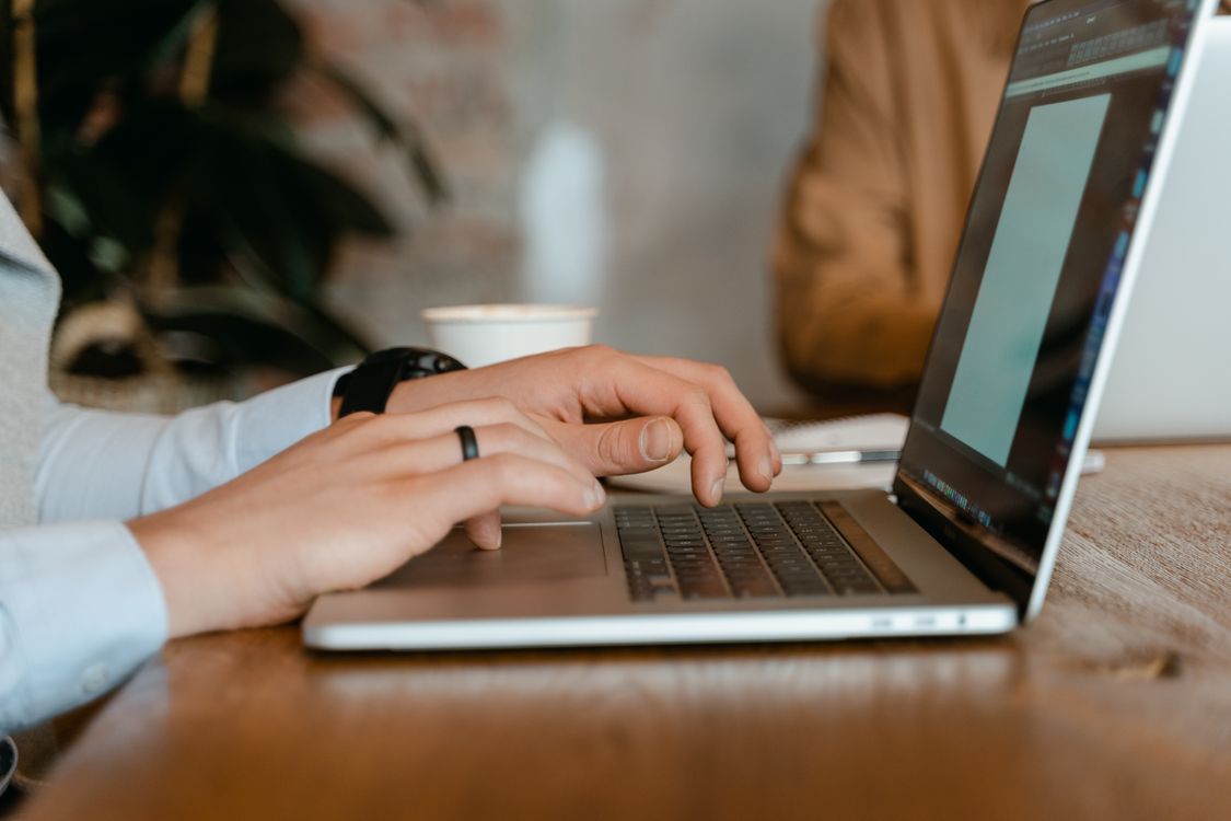 Hands typing on a laptop at a desk with coffee