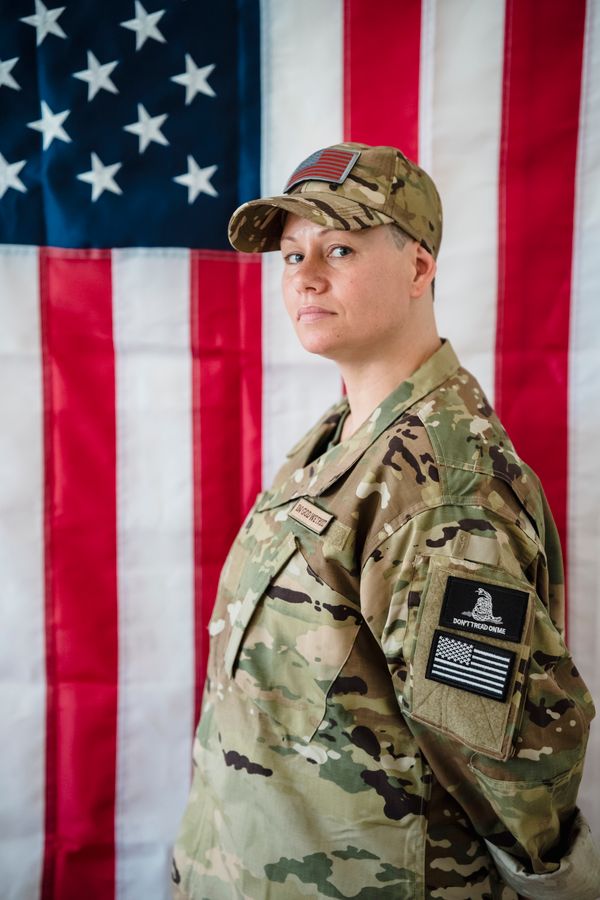 Woman veteran in Army uniform standing in front of the American flag